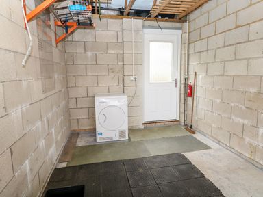 A utility room with a dryer a broom foam floor mats and a door at 20 Bishops Way in Falmouth