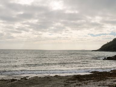 A beach with sand and seaweed with the ocean and a cloudy sky at 20 Bishops Way in Falmouth
