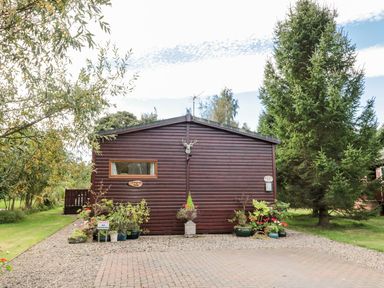 A wooden cabin with plants in pots and a private no parking sign at Evergreen Lodge Felmoor Holiday Park near Felton