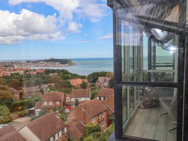 View of a residential area with houses trees and a coastline visible through a window at The Penthouse in Scarborough