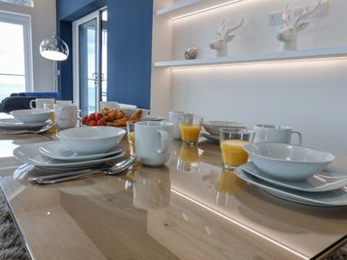 A dining table set with white plates bowls mugs and glasses of orange juice at The Penthouse in Scarborough