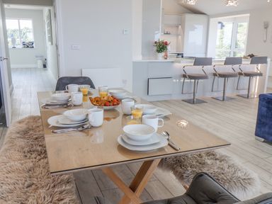A dining table with plates cups cutlery and glasses of orange juice next to a kitchen counter with bar stools at The Penthouse in Scarborough