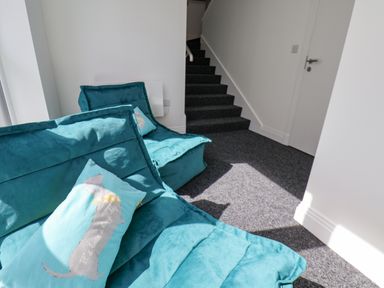 A seating area with blue chairs and a dog-themed pillow near carpeted stairs in a white room at The Penthouse in Scarborough