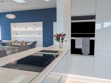 A modern kitchen with an induction cooktop a dining table set for breakfast and built in ovens at The Penthouse in Scarborough