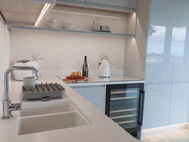 A kitchen counter with a sink toaster wine bottle cutting board and kettle at The Penthouse in Scarborough
