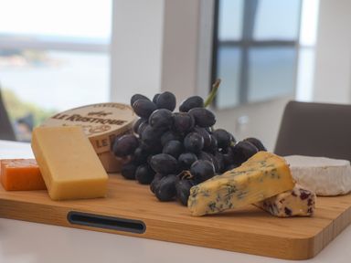 A wooden board with an assortment of cheese and a bunch of black grapes at The Penthouse in Scarborough