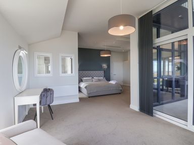 A bedroom with a bed desk two chairs and large windows at The Penthouse in Scarborough