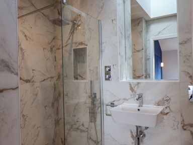 A bathroom with a glass shower enclosure a white sink and a mirror at The Penthouse in Scarborough