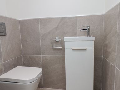 A small bathroom with a toilet and a white sink unit at The Penthouse in Scarborough