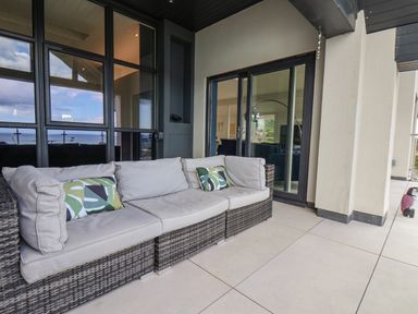 An outdoor patio with a wicker sofa and cushions near sliding glass doors at The Penthouse in Scarborough