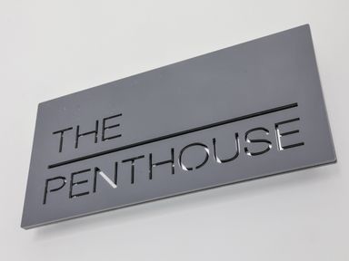 A black rectangular sign with cutout letters spelling the penthouse on a white wall at The Penthouse in Scarborough