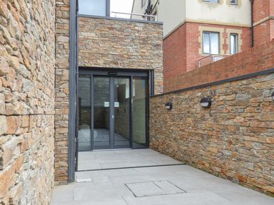 A stone walled outdoor corridor with automatic glass doors at The Penthouse in Scarborough