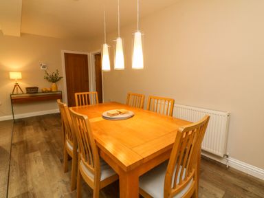 A dining room with a wooden table and six chairs under three hanging lights at Spicery in Tedburn St Mary