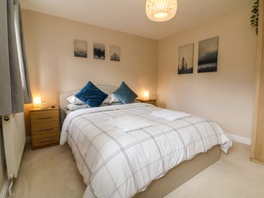 A bedroom with a double bed two bedside tables and framed pictures on the walls at Spicery in Tedburn St Mary