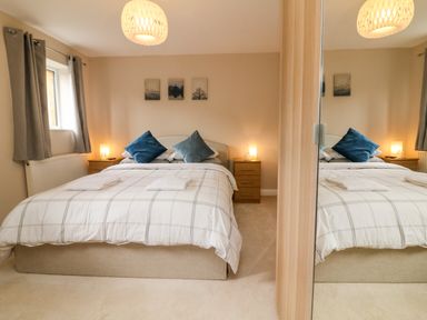 A bedroom with a double bed with pillows bedside tables lamps and a wardrobe with mirrored doors at Spicery in Tedburn St Mary