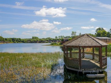 A gazebo on a lake with houses and trees in the background at Lakeside 20 in Warton near Carnforth
