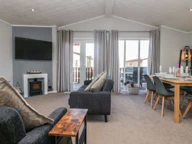 A living room with sofas a wall mounted TV and dining table with chairs at Lakeside 20 in Warton near Carnforth