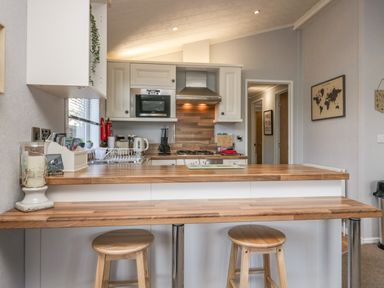 A kitchen with wooden countertops stools a microwave sink and wall cabinets at Lakeside 20 Warton near Carnforth