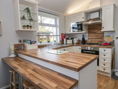 A kitchen with wooden countertops white cabinets and appliances at Lakeside 20 in Warton near Carnforth
