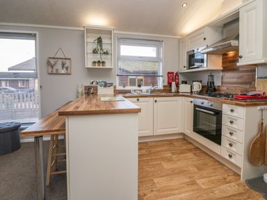 A kitchen with wooden countertops white cabinets a stove oven microwave and a window at Lakeside 20 in Warton near Carnforth