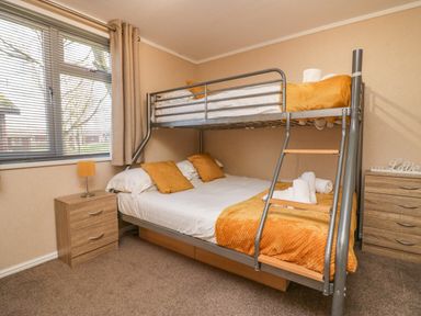 A bedroom with a bunk bed next to a window and wooden bedside tables at Lakeside 20 in Warton near Carnforth