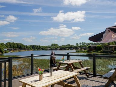 A lakeside view with wooden picnic tables and glass railing at Lakeside 20 in Warton near Carnforth