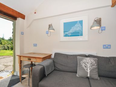 A seating area with a table and artwork at Little Coombe in Trehunist near Liskeard