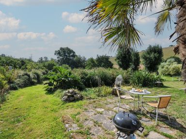 A garden with a table and chairs at Little Coombe in Trehunist near Liskeard