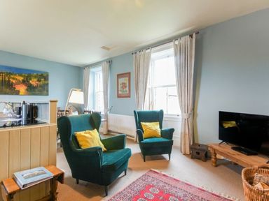 A living room with two armchairs and a TV at Riverbank Cottage in Alnmouth