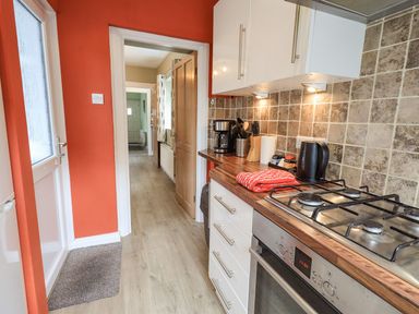 A kitchen with a gas stove coffee maker kettle and utensils on wooden counter at Woolly End Cottage in Ambleside