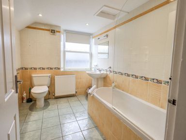 A bathroom with a toilet sink and bathtub with tiled walls and floor at Woolly End Cottage in Ambleside