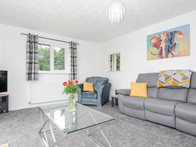 A living room with a gray sofa and blue armchair with yellow cushions at The Old Forge in Trerulefoot