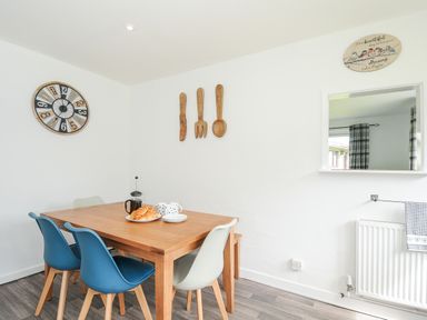 A dining area with a wooden table and blue and white chairs croissants on a plate and wall decorations at The Old Forge in Trerulefoot