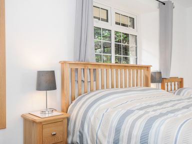 A bedroom with a wooden bed frame striped bedding bedside tables and lamps at The Old Forge in Trerulefoot