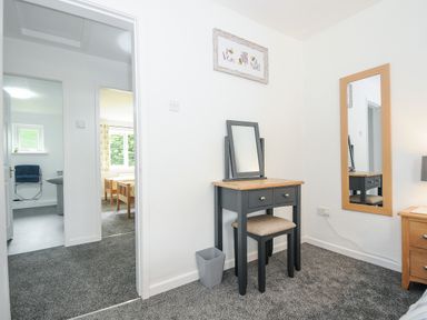 A bedroom corner with a dressing table stool and mirror and a full length wall mirror at The Old Forge in Trerulefoot