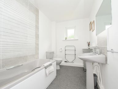 A bathroom with bathtub toilet sink mirror and small window at The Old Forge in Trerulefoot
