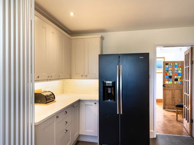 A kitchen with white cabinets a black refrigerator and a bread box at Ayr Farmhouse in St Ives