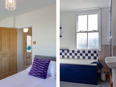 A bedroom with a bed and a purple pillow next to a bathroom with a blue bathtub and a window at Ayr Farmhouse in St Ives