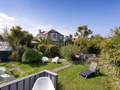 A garden with outdoor chairs and a stone house in the background at Ayr Farmhouse in St Ives