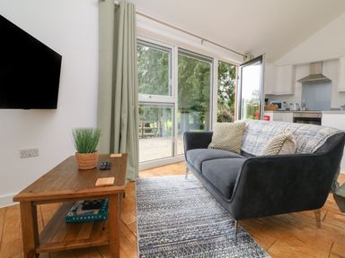 A living room with a gray sofa and wooden coffee table near sliding glass doors at Jasmine Bydown near Barnstaple