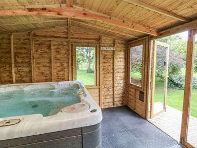 A wooden room with a hot tub and an open door leading outside at Jasmine Bydown near Barnstaple