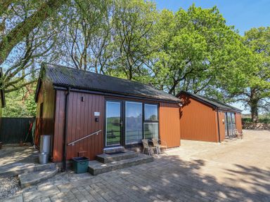A cabin with patio area and chairs at Jasmine in Bydown near Barnstaple
