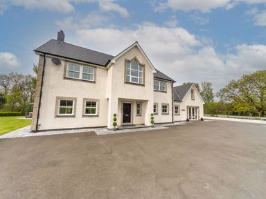 A large white house with multiple windows and a black front door with small green bushes on either side in a paved driveway at Parc Y Deri in Rhos-y-garth near Aberystwyth