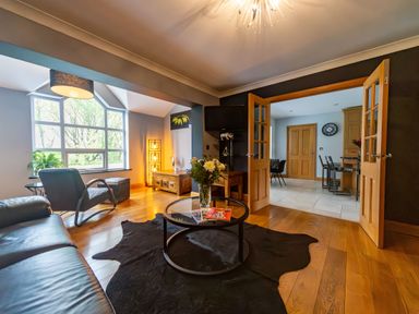 A living room with a leather sofa armchair glass coffee table and large window at Parc Y Deri in Rhos-y-garth near Aberystwyth