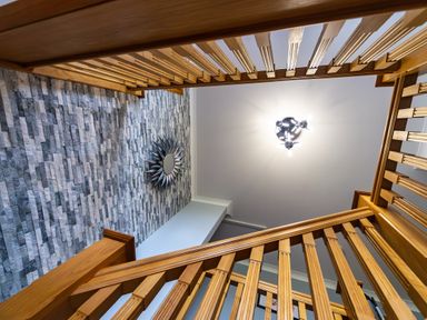A wooden staircase with a stone accent wall and a modern ceiling light at Parc Y Deri in Rhos-y-garth near Aberystwyth