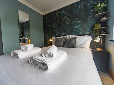 A bedroom with a bed with folded towels on it and a mirror on the wall at Parc Y Deri in Rhos-y-garth near Aberystwyth