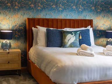 A bedroom with a bed with white linens blue pillows and lamps on wooden bedside tables at Parc Y Deri Rhos-y-garth near Aberystwyth