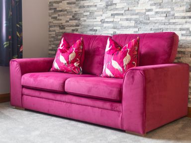 A sofa with two cushions in front of a stone wall in Parc Y Deri Rhos-y-garth near Aberystwyth