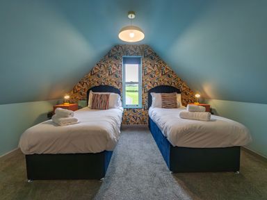 A bedroom with two single beds bedside tables and a central window at Parc Y Deri in Rhos y garth near Aberystwyth