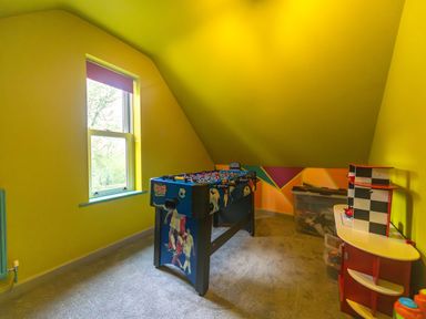 A playroom with a foosball table next to a window and a toy kitchen at Parc Y Deri in Rhos-y-garth near Aberystwyth